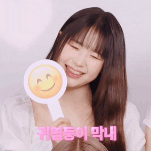 a girl holding a paddle with a smiley face on it and a foreign language behind her