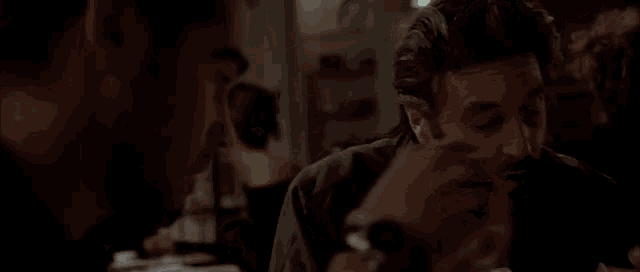 two men are sitting at a table in a dark room eating .