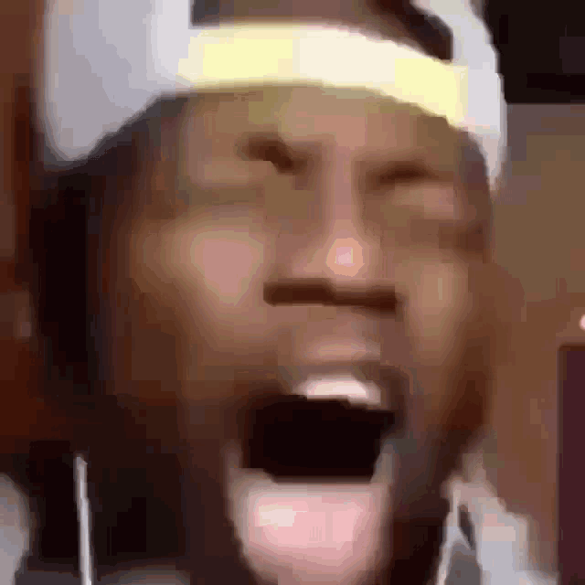 a man wearing a hat and headphones is screaming with his mouth wide open .