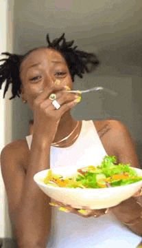 a woman is eating a salad with a fork and a spoon .