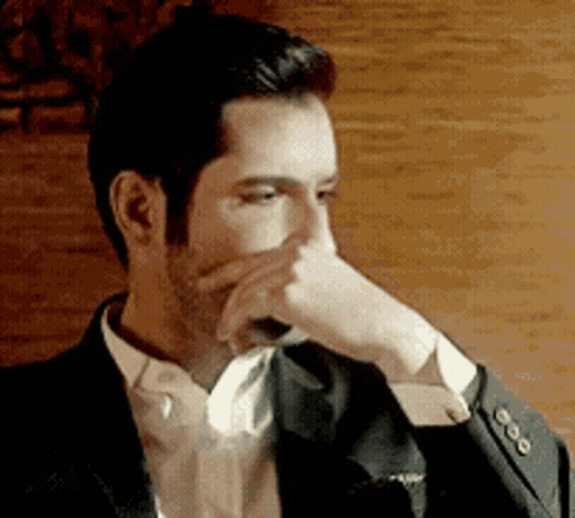 a man in a suit and tie is covering his nose with his hand