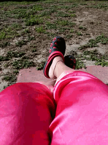 a person wearing pink pants and black shoes is standing on a sidewalk