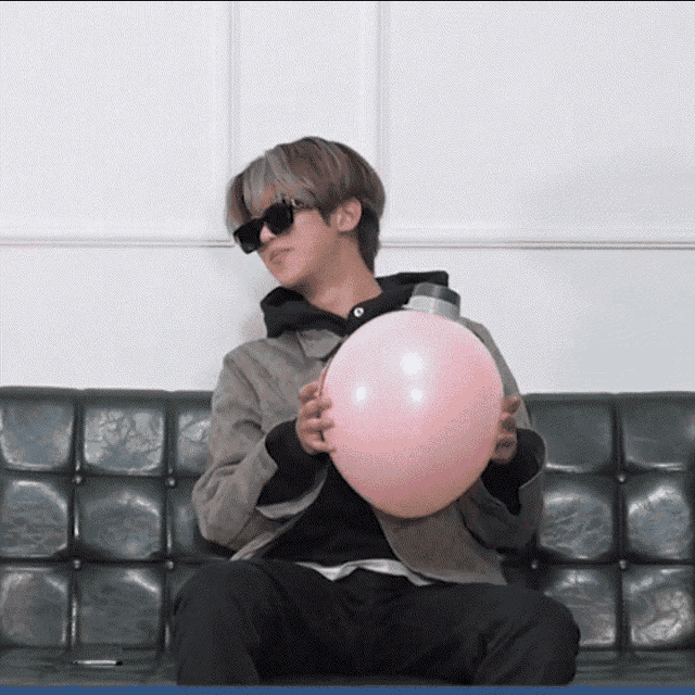 a man wearing sunglasses is holding a pink balloon