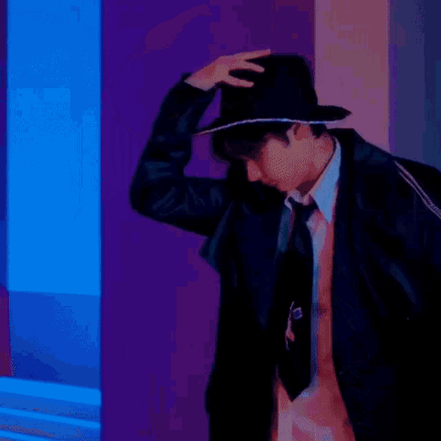 a young man wearing a hat and a tie is standing in a room .