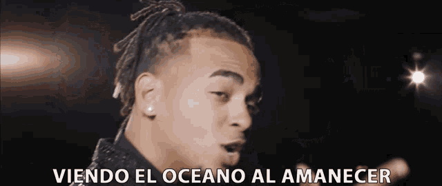 a close up of a man with the words viendo el oceano al amanecer on the bottom