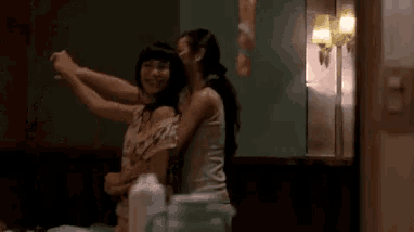 two women are dancing together in a room and holding hands .