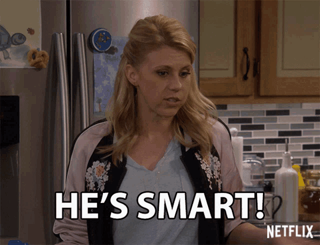 a woman says he 's smart while standing in front of a refrigerator