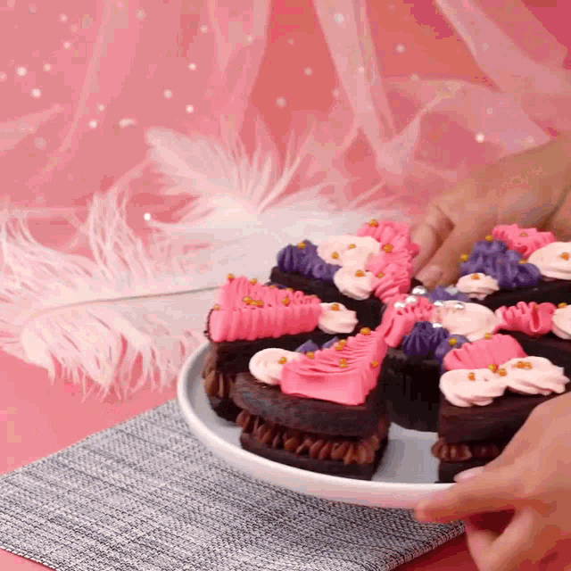 a person is taking a piece of cake from a plate with pink and purple frosting