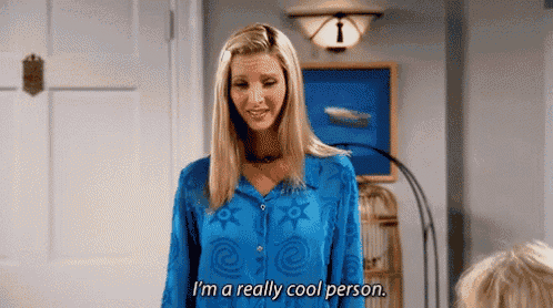 a woman in a blue shirt is standing in a room and says `` i 'm a really cool person . ''