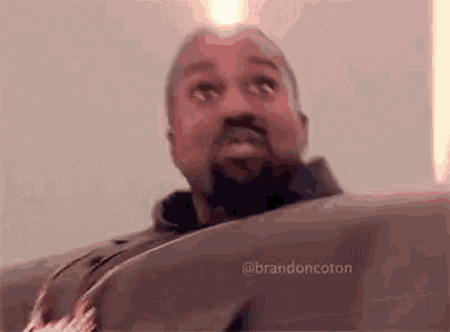 a man with a beard is sitting on a couch and looking at the camera .