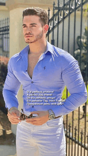 a man in a blue shirt is standing in front of a wrought iron gate