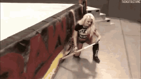 a woman is kneeling down in a wrestling ring holding a hammer .