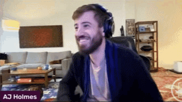 a man wearing headphones is smiling in a living room with aj holmes written in the corner