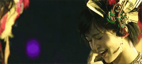a woman with a flower in her hair is holding a microphone and crying .