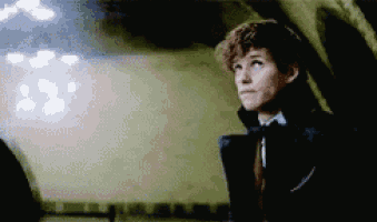 a young man in a suit and tie is standing in a dark room looking up .