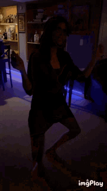 a woman in a red dress is dancing in a living room with a poster on the wall that says monopoly on it