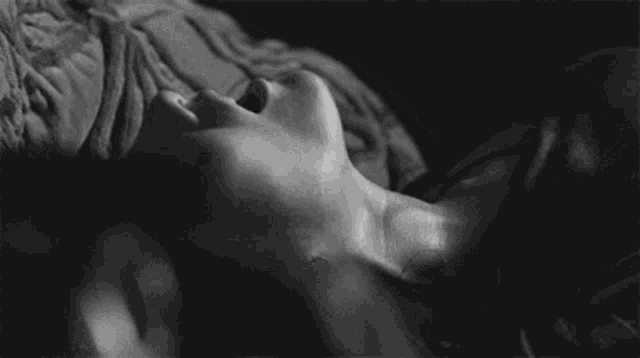 it is a black and white photo of a woman laying down with her mouth open .