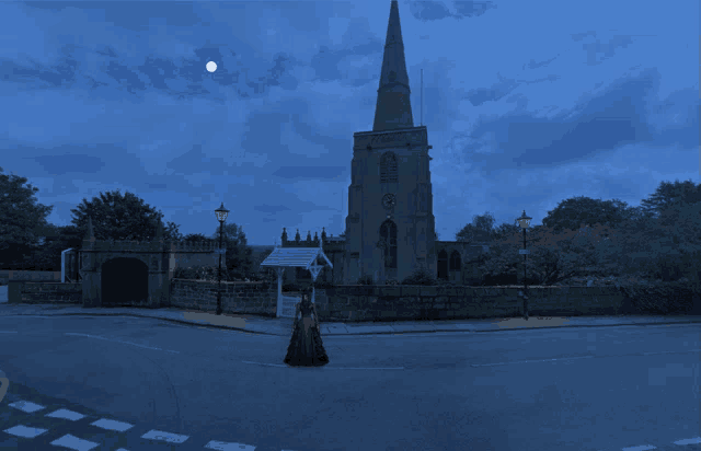 a woman in a long dress stands in front of a church