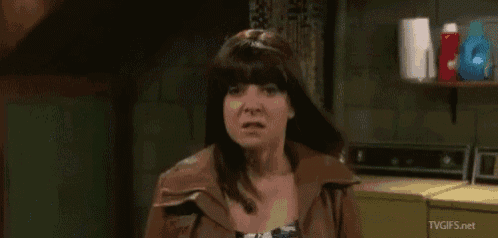 a woman in a leather jacket is standing in a laundry room next to a washer and dryer .
