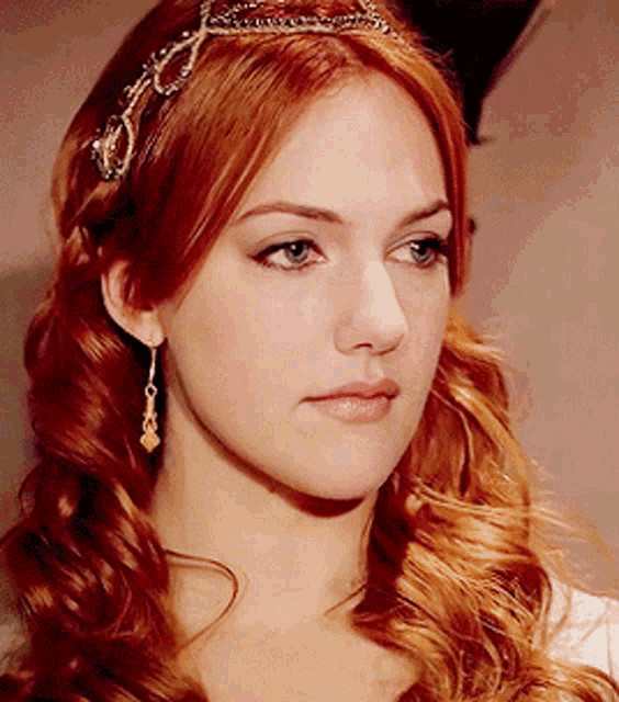a close up of a woman 's face with red hair and earrings