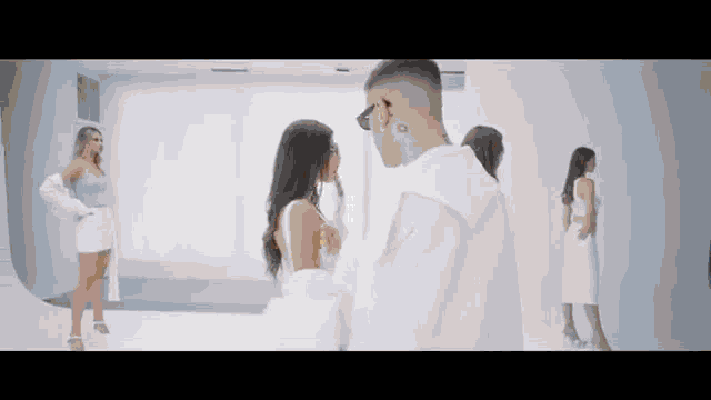 a man in a white shirt is standing next to a woman in a white dress in a room .