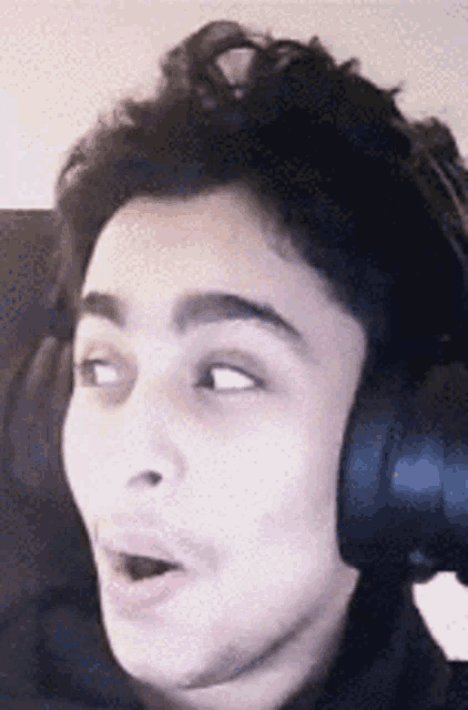 a close up of a person wearing headphones making a funny face .