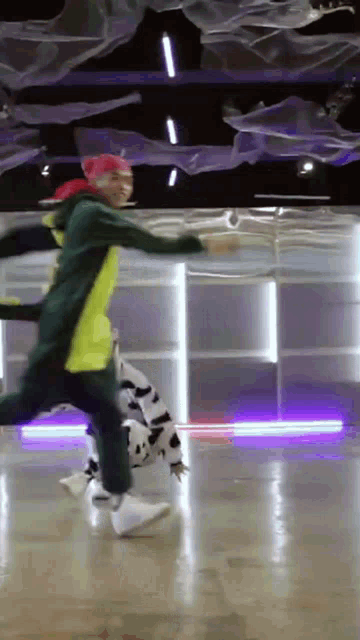 a man in a yellow and green jacket is dancing with a cow costume on .