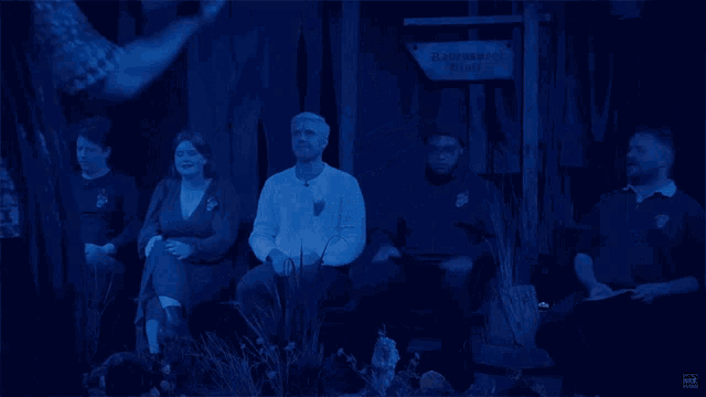 a man holding a box in front of a group of people in a dark room