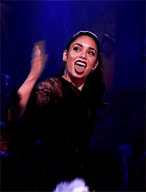 a woman in a black top and denim shorts is making a funny face