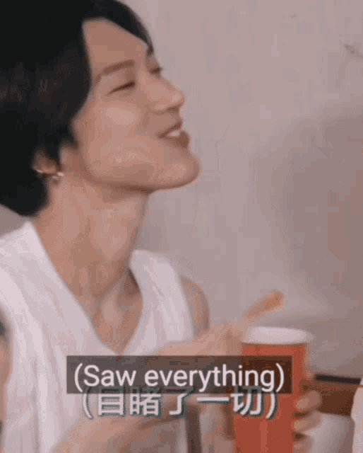 a man in a white tank top is holding a red cup that says saw everything on it