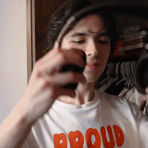 a man wearing a shirt that says proud holds something in his hand