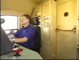 a man in a blue shirt is driving a vehicle
