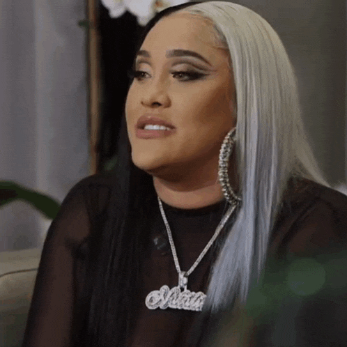 a woman with long white hair is wearing a necklace with the name olivia on it .