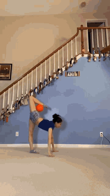 a woman is doing a handstand while holding a ball