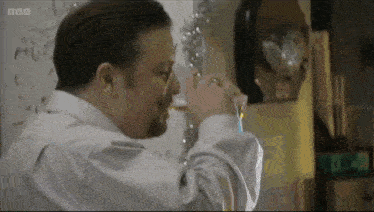 a man drinking from a glass with the bbc logo on the bottom right