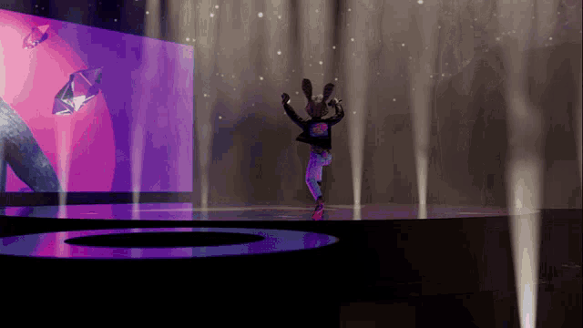 a cartoon character is dancing on a stage with a large screen in the background