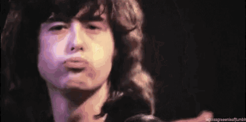 a close up of a man making a funny face while playing a guitar .