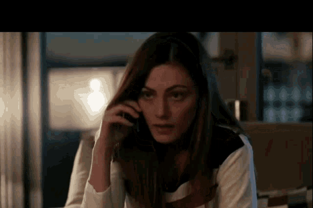 a woman is talking on a cell phone while looking at the camera