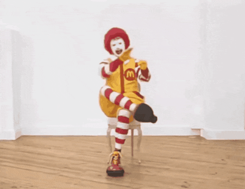a mcdonald 's clown is sitting in a chair