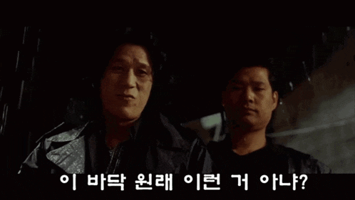 two men are standing next to each other in the rain in a movie .