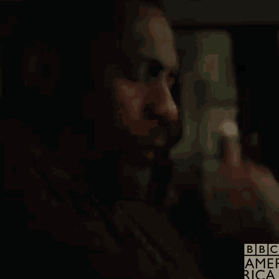 a close up of a man 's face in a dark room talking on a cell phone .