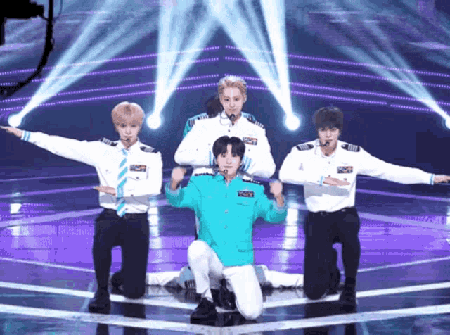 a group of young men are performing on a stage and one of them is wearing a blue jacket that says ' captain '