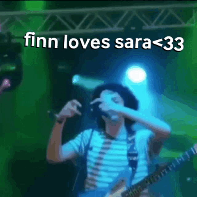a man singing into a microphone with the words finn loves sara < 33 written above him