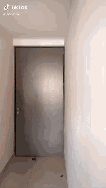a gray door in a hallway with tiktok written on the bottom right