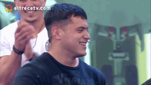 a man in a black shirt is smiling in front of an eltrecetv.com logo