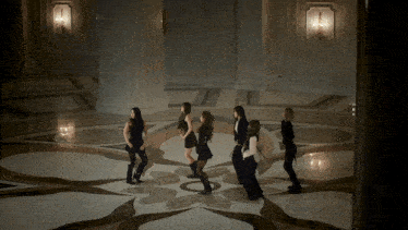 a group of women are dancing in a room with a patterned floor
