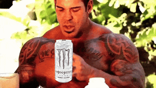 a muscular man is holding a can of monster energy drink .