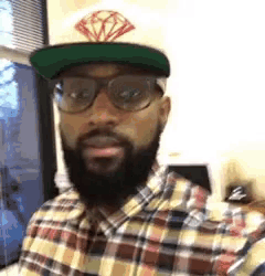 a man with a beard wearing a plaid shirt and a hat with a diamond on it .