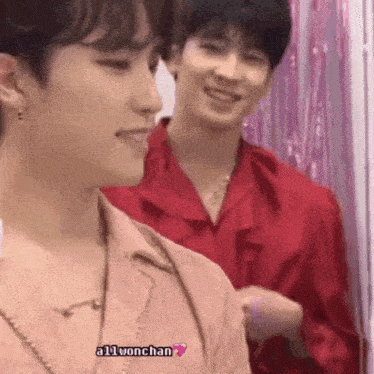 a couple of young men are standing next to each other and smiling .