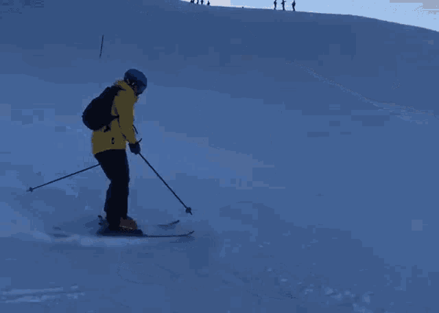 a person skiing down a snowy slope wearing a yellow jacket and a blue helmet